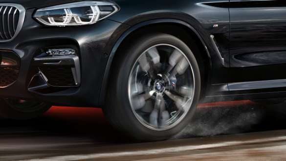 BMW X3 M40i and BMW X3 M40d, side view. BMW X3 M40i and BMW X3 M40d in Black Sapphire metallic, driving, exterior, side view with rotating light alloy wheel.