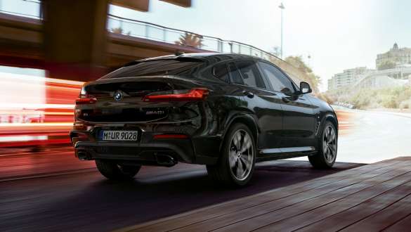 BMW X4 M40i and BMW X4 M40d, three-quarter rear view. BMW X4 M40i and BMW X4 M40d in Black Sapphire metallic, driving, exterior, three-quarter rear view with light strips.