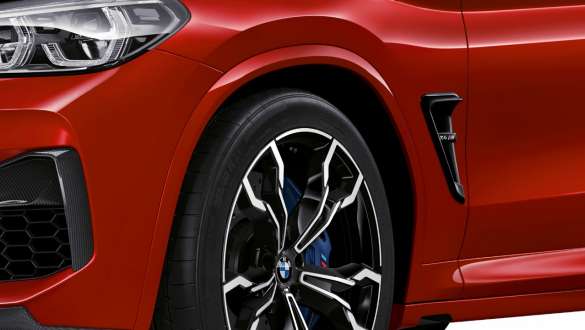 BMW X4 M Competition, close-up view lateral rear. BMW X4 M Competition in Toronto Red metallic, exterior, close-up view lateral rear, M specific suspension.
