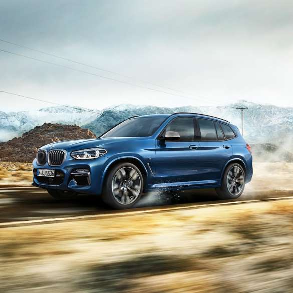 BMW X3 M40i, medium shot rim and front fender in front of mountain BMW X3 M40i, medium shot rim and front fender in front of mountain