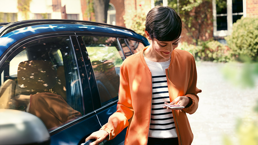 BMW Service Woman with smartphone next to the door of her BMW BMW Service Woman with smartphone next to the door of her BMW