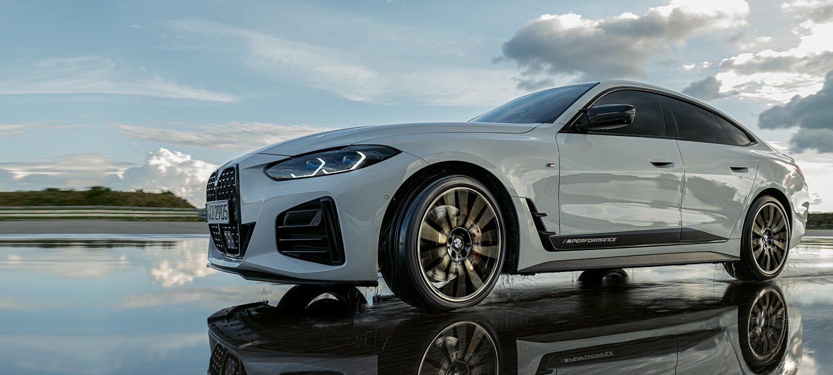 BMW 4 Series Gran Coupé (G26) with M Performance Parts driving on wet street BMW 4 Series Gran Coupé (G26) with M Performance Parts driving on wet street