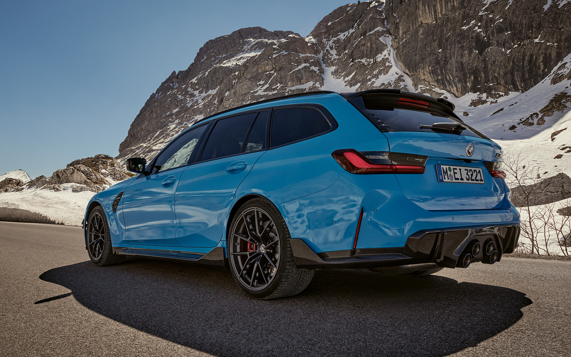BMW M3 Touring G81 BMW M Performance Parts three-quarter side view driving BMW M3 Touring G81 BMW M Performance Parts three-quarter side view driving in front of mountain landscape