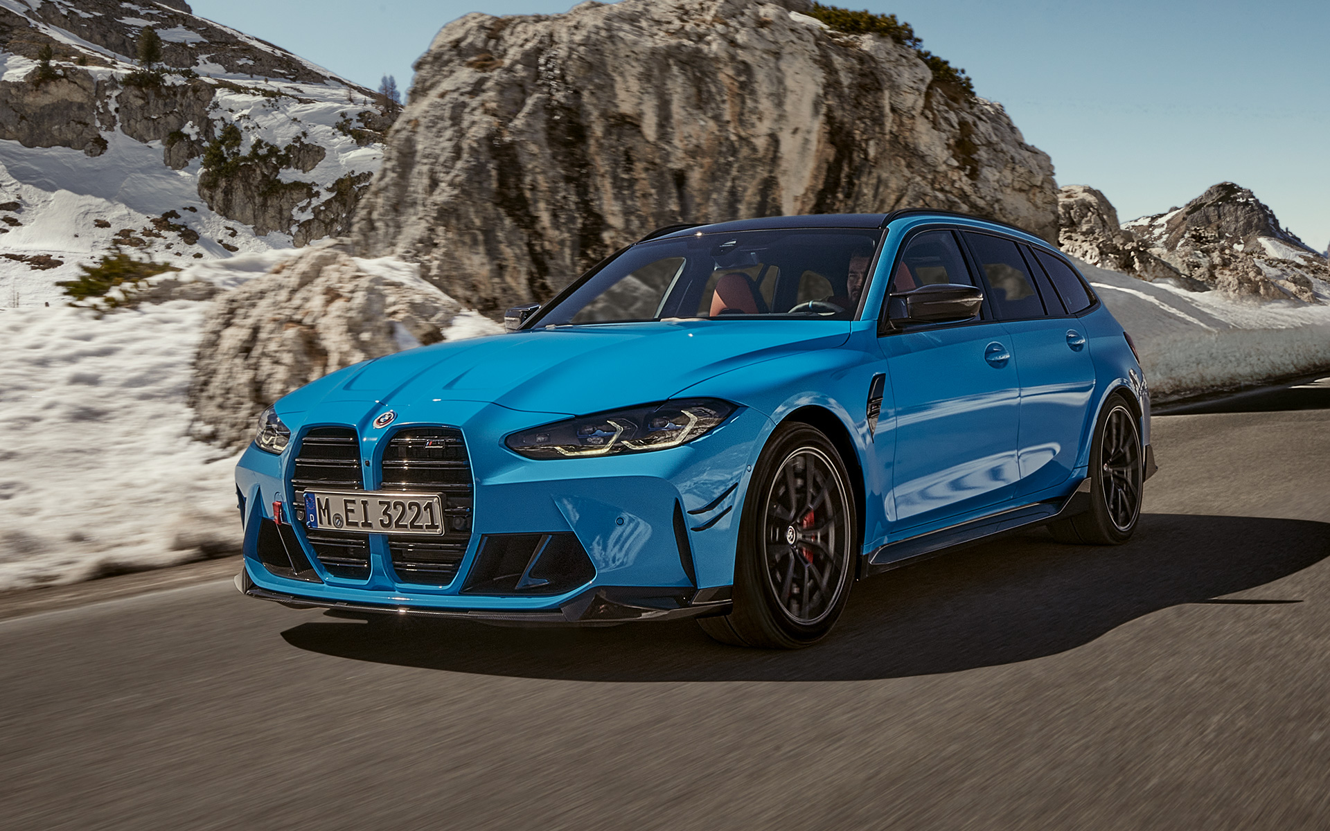 BMW M3 Touring G81 BMW M Performance Parts three-quarter front view driving BMW M3 Touring G81 BMW M Performance Parts three-quarter front view driving in front of mountain landscape