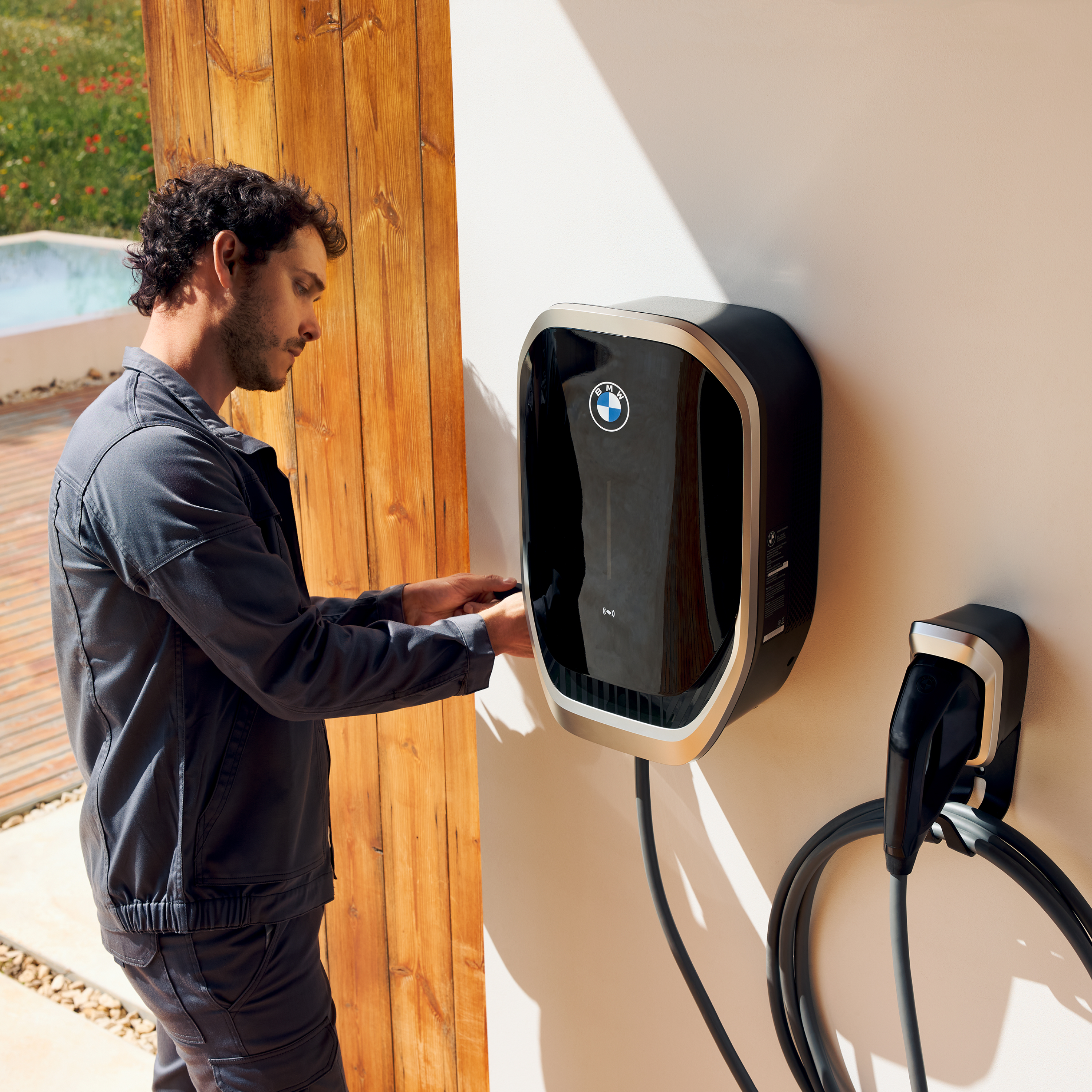 A person is connecting a charging cable to a BMW wallbox